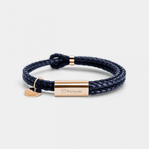 Navy braided bracelet with a gold tag and heart charm on a light gray background