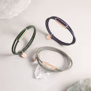 Three braided bracelets in green, purple, and gray on a light background