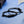 Black braided bracelet with metal tags on a blue surface