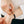 Person adjusting a black bracelet with a rose gold clasp on a white background
