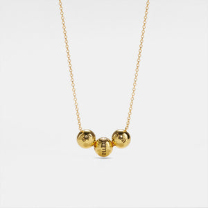 Gold necklace with three round pendants on a white background