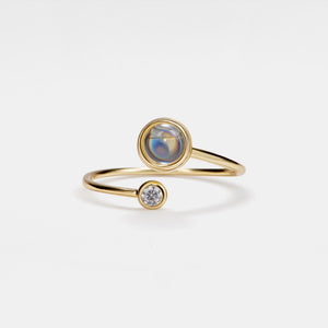 Gold ring with a gemstone and smaller diamond on a light gray background