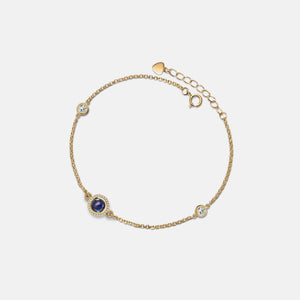 Gold bracelet with gemstones on a light gray background