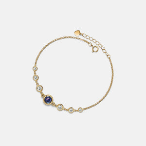 Gold bracelet with gemstones on a light gray background