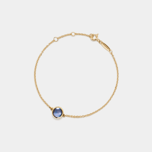 Gold bracelet with a projection gemstone on a light gray background