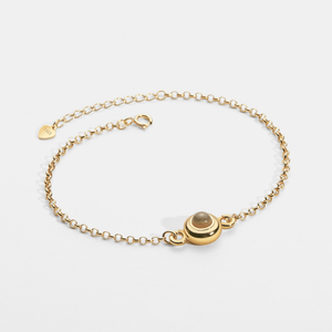 Gold bracelet with a round clasp on a light gray background