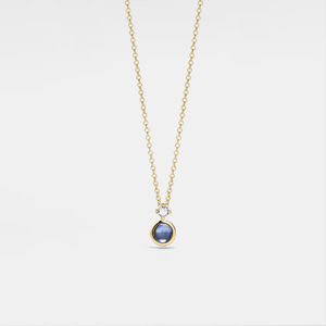 Gold necklace with a projection gemstone pendant on a light gray background