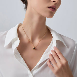 Necklace with a pendant worn by a person in a white shirt against a neutral background