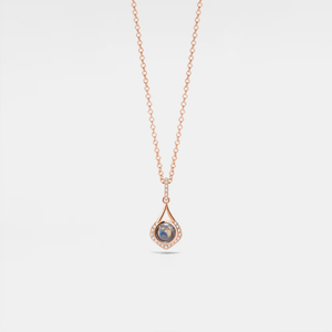 A rose gold-plated sterling silver charm necklace with a teardrop-shaped pendant featuring a photo projection, suspended from a delicate chain.