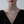 Woman wearing a gold necklace with a projection gemstone pendant on a light gray background