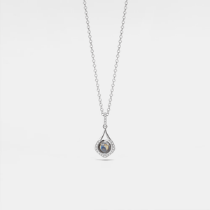 A white gold-plated sterling silver charm necklace with a teardrop-shaped pendant featuring a photo projection, suspended from a delicate chain.