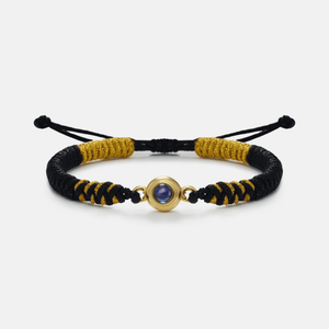 Bracelet with black and gold cord and a gold clasp on a white background