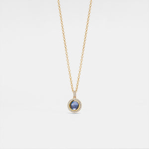 Gold necklace with a blue gemstone pendant on a light gray background