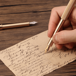 Hand writing on an old letter with a gold pen on a wooden surface