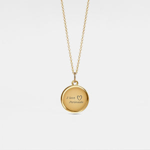 Gold necklace with a round locket pendant on a light gray background