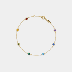 Gold bracelet with colorful gemstones on a light gray background