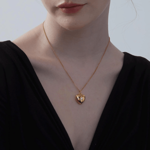 Woman wearing a gold heart-shaped locket necklace with a star and diamond on a light gray background
