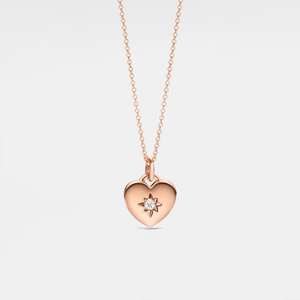 Rose gold heart-shaped locket necklace with a star and diamond on a light gray background