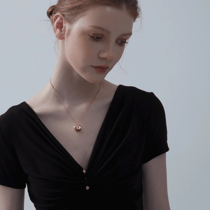 Woman wearing a gold heart-shaped locket necklace with a star and diamond on a light gray background