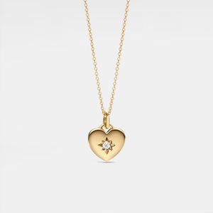 Gold heart-shaped locket necklace with a star and diamond on a light gray background