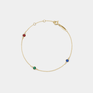 Gold bracelet with colorful gemstones on a light gray background