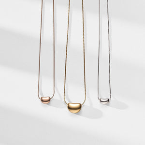 Three necklaces with different pendants on a white background