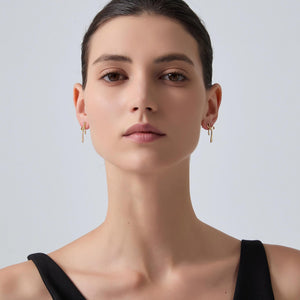 Woman wearing gold earrings against a plain background