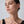 Woman wearing gold earrings against a plain background