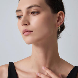 Woman wearing gold earrings against a plain background