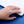 Hand wearing a silver ring with a blue gemstone on a white surface.