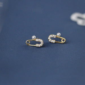 Gold safety pin earrings with pearls on a blue background
