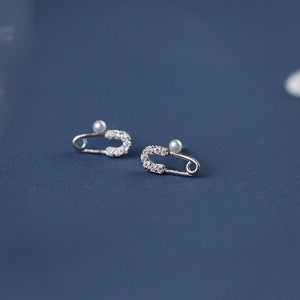 Pair of silver earrings with pearl accents on a blue background