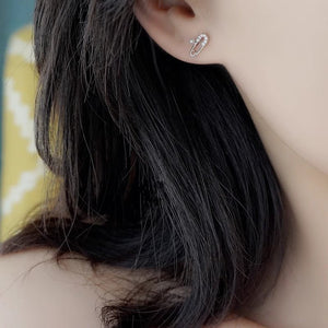 Close-up of an earring worn by a person with dark hair.