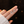 Silver earrings held on a hand against a dark background