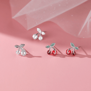 Cherry-themed earrings on a pink background