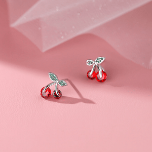 Cherry-themed earrings on a pink background