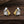 Pair of earrings featuring a silver figure with a gold dog on a wooden surface