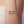 A bracelet with two dachshund charms on a wrist against a neutral background