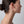 Woman wearing a gold hoop earring on a plain background
