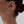 Gold hoop earring worn by a person with a neutral background