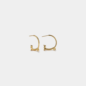 Gold hoop earrings with cat-shaped ends on a light gray background