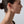 Close-up of a woman wearing a gold hoop earring against a neutral background