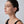 Woman wearing a gold earring on a plain background