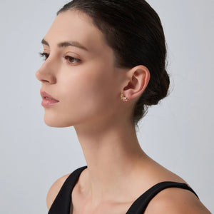 Woman wearing a gold earring on a plain background