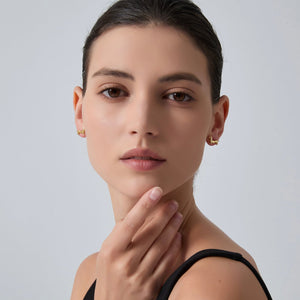Woman wearing gold earrings with a neutral background