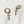 Gold hoop earrings with sword-shaped charms on a white textured background