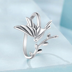 Silver bird-shaped ring on a light blue background