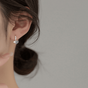 Silver earring worn by a person with a neutral background