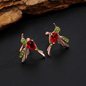 Pair of earrings with red and green gemstones on a dark surface