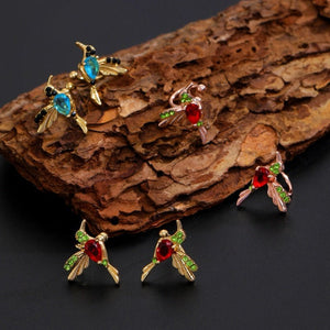 Colorful insect-shaped earrings on a textured wooden surface